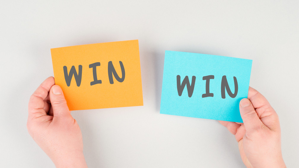 Due cartoncini tenuti da due mani uno a sinistra con la scritta Win e uno a destra con la scritta win