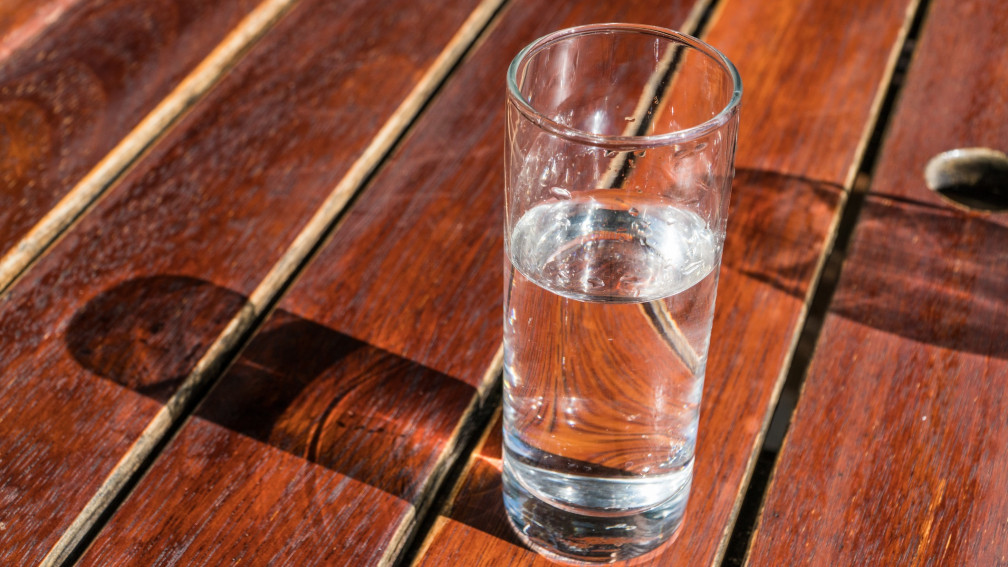 Halbvolles Wasserglas auf Holztisch