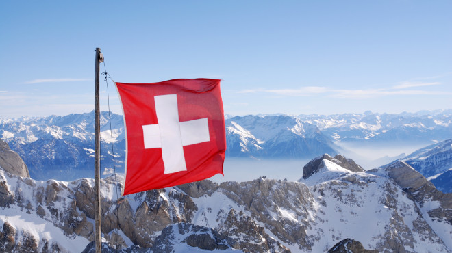 Schweizer Flagge mit verschneiten Bergen im Hintergrund