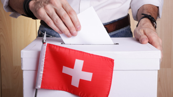 urna di voto con bandiera svizzera in primo piano