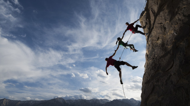 Kletterer halten sich gegenseitig fest am Seil