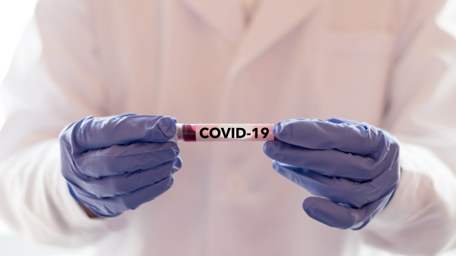 Doctor holding a vial that says "covid 19)