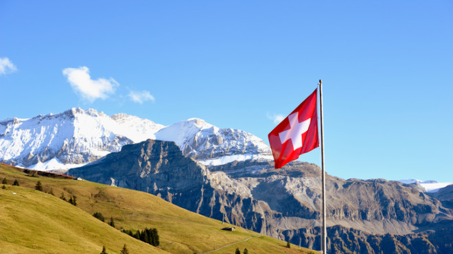 Schweizer Flagge im Vordergrund der Alpen