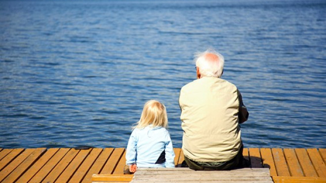 alter Mann und Kind blicken auf See