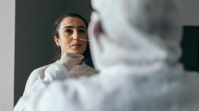 Mediziner nimmt Abstrich aus der Nase einer junger Frau