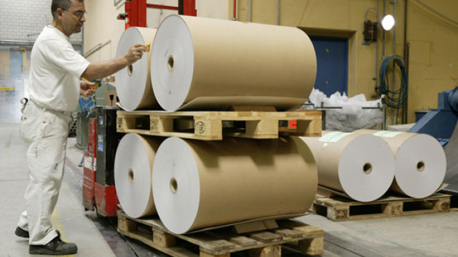 Mann mit Papierrolle in Papierfabrik