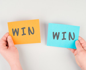 Due cartoncini tenuti da due mani uno a sinistra con la scritta Win e uno a destra con la scritta win