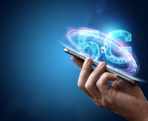 Digitaler Schriftzug "5g" fliegt über Handy das von einer Hand gehalten wird