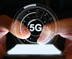 Person tippt auf Handy über dem ein digitales 5G Symbol schwebt