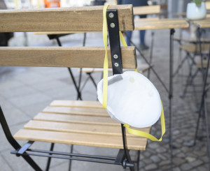 Atemschutzmaske hängt über leerem Stul vor einem Restaurant