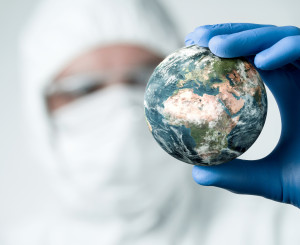 Forscher mit Gesichtsmaske hält Globus in einer Hand