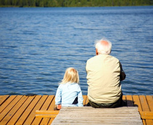 alter Mann und Kind blicken auf See