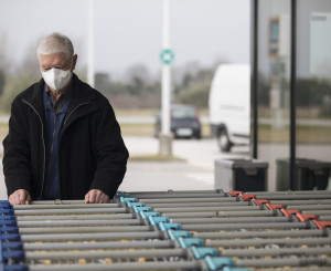 Mann mit Atemschutzmaske räumt Einkaufswagen ein