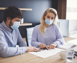 Man and woman work at a desk wearing masks