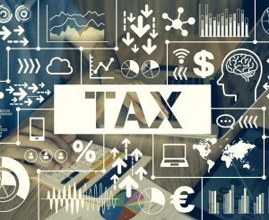 digitaler Bildschrim in der Mitte das Wort Tax, also Steuer